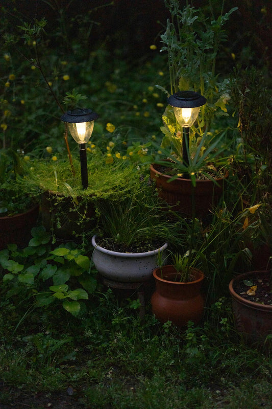 Solarne lampy ogrodowe wśród doniczek z roślinami